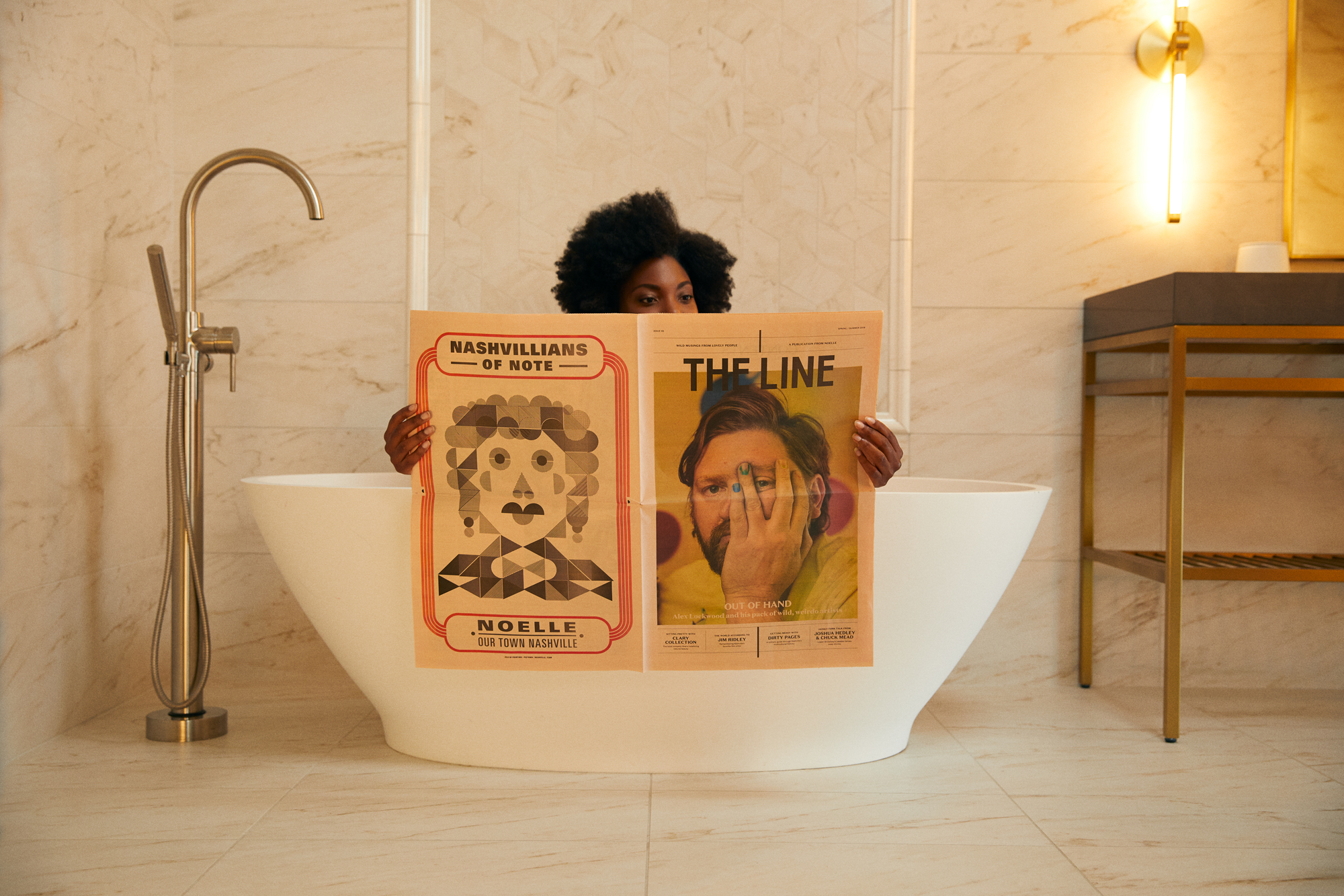 A woman in a bathtub reading a newspaper